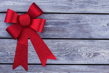 Red shiny bow on rustic background. Christmas bow on wooden boards with copy space. Holiday...