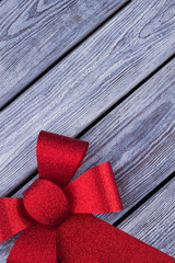 Red shiny bow ribbon with copy space. Big Red Christmas bow on rustic wooden boards with text space. Happy holiday card.