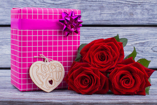 Flowers and gift box on wooden background. Flowers, wooden heart and present box. Valentine holiday concept.