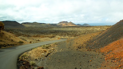winding road through a volcanic landscape with a crater in the distance