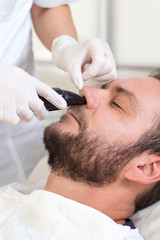 Obraz na płótnie Canvas Mężczyzna w salonie kosmetycznym podczas zabiegu usuwania owłosienia z nosa