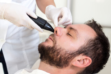 Obraz na płótnie Canvas Mężczyzna w salonie kosmetycznym podczas zabiegu usuwania owłosienia z nosa