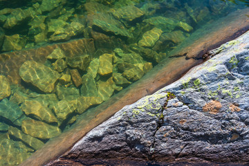 Close-up of a mountain lake in the Alps with cold crystal clear water and a seabed of rocks