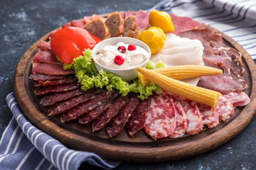 Different sausages with pickled vegetables on wooden board. Tasty cold snack. Closeup