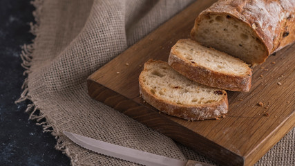 Appetizing sliced ciabatta bread  on wooden board with copy space