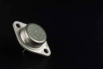Radio element, a very old diode close-up, against a dark background.