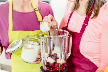 Happy smiling friends making fresh fruit milkshake in the blender