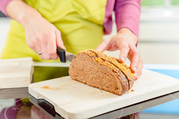 Close-up of woman cutting healthy bread for sandwich
