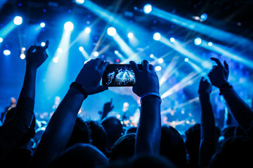 fan taking photo with cell phone at a concert.