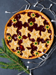 Christmas home sweet cake with jam on dark background, garland. Green branches of a Christmas tree. Vertical photo