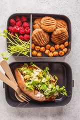 Healthy meal prep containers with quinoa Stuffed Sweet Potatoes, cookies and berries, overhead shot.