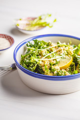 Kale, quinoa, avocado vegan salad in a white bowl on a white background.