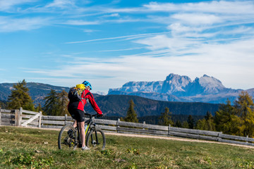 Frau auf Mountainbike fährt über Wiese mit Blick in die Berge