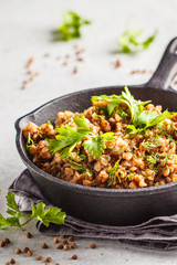 Buckwheat with meat in a cast iron pan on a white background.