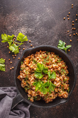 Buckwheat with meat in a cast iron pan on a dark background, copy space, top view,