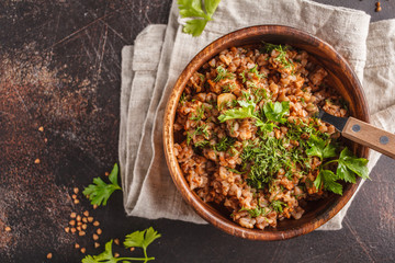 Buckwheat with meat in a wooden bowl on a dark background, top view, copt space.