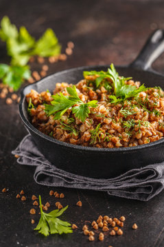 Buckwheat with meat in a cast iron pan on a dark background, copy space.