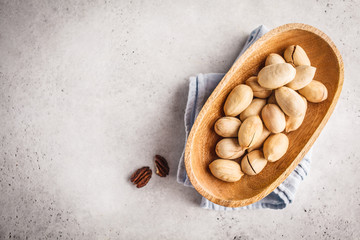 Pecan nuts in a wooden bowl on a white background, top view, copy space.