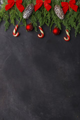 Christmas composition of coniferous branches, decorations and sweets on dark background. Flat lay. Top view Nature New Year concept. Copy space.