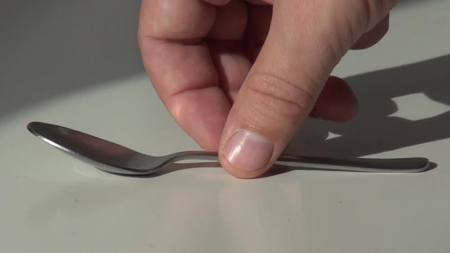 hand puts a teaspoon on the table and takes