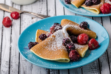 Homemade crepes with frozen berries, topped sugar