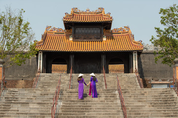 Fototapeta premium Traditionally dressed Vietnamese young women climb the stair of historical Khiem Cung Palace ( Tomb ).
