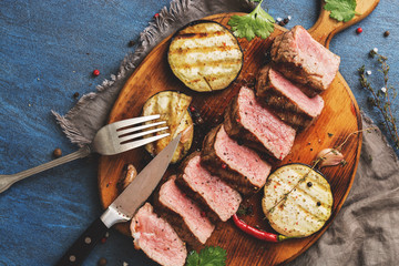 Grilled beef steak medium with vegetables on a cutting board. Top view, flat lay.