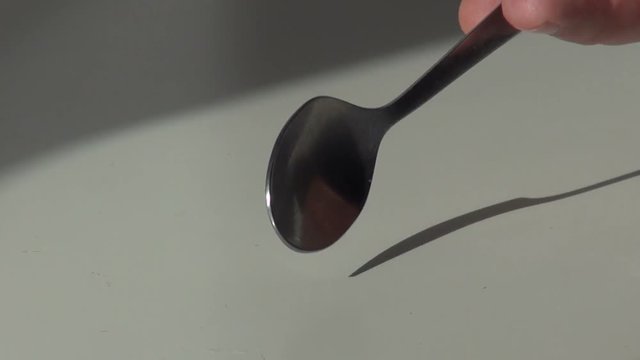 hand knocking a teaspoon on the table