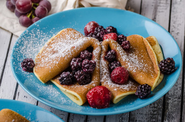 Homemade crepes with frozen berries, topped sugar