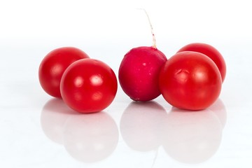 Odd one out. Cherry Tomatoes and a Radish against a white background