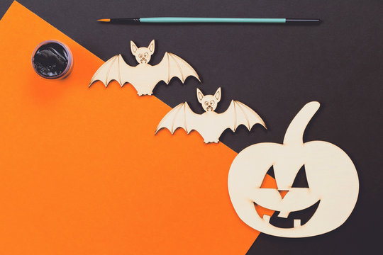 Do it yourself Halloween pumpkin and vampire bats wooden cut outs flat lay with copy space, orange paint and brush