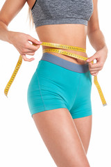 Diet concept. Perfectly slim girl measures her waist with a tape. Studio, white background.
