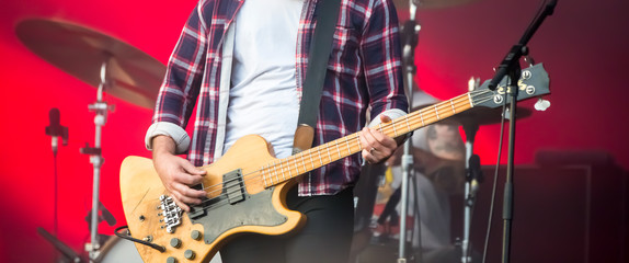 Man guitarist bass guitar instrument performing at stage rock music.
