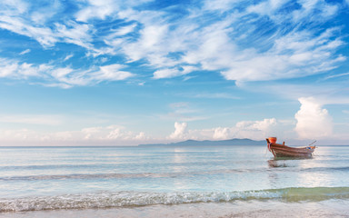 Obraz premium beautiful beach in morning sunrise and cloudy blue sky with fisherman boat