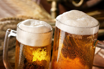 Two glass of beer .With wheat and barley and barrels spikes on bakcground.Closeup selective focus