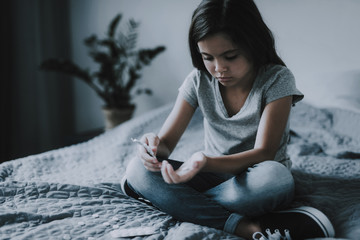 Little Girl Sits on Bed with Scattered Pills