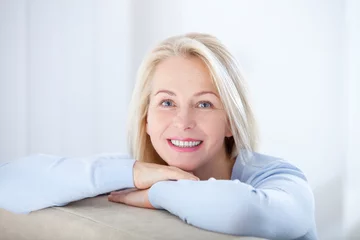 Poster Active beautiful middle-aged woman smiling friendly and looking in camera. Woman's face closeup. Realistic images without retouching with their own imperfections. Selective focus. © missty