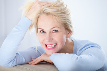 Fototapeta premium Active beautiful middle-aged woman smiling friendly and looking in camera. Woman's face closeup. Realistic images without retouching with their own imperfections. Selective focus.
