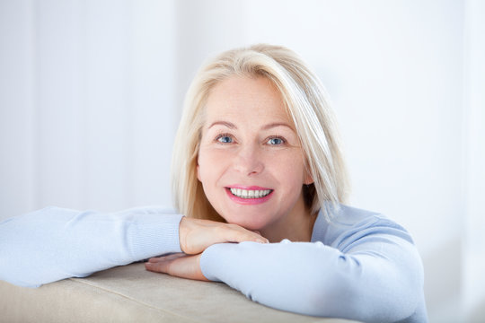 Fototapeta Active beautiful middle-aged woman smiling friendly and looking in camera. Woman's face closeup. Realistic images without retouching with their own imperfections. Selective focus.
