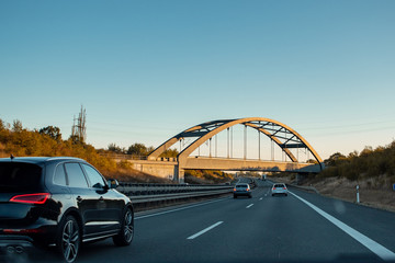 Driving in the morning on the german autobahn highway with a bridge and cars. Road trip scenery