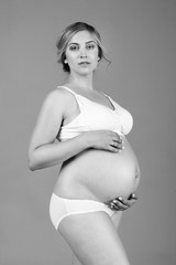Beautiful pregnant woman in white underwear for pregnancy and lactation. Black and white photo.