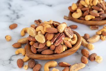 roasted mixed nuts in wooden bowl on barble table background.