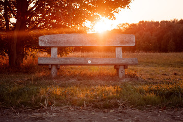 Bright orange summer sunset light view of a bench in the nature is a relax location to enjoy the evening in the remote landscape. Braunschweig, Lower Saxony in Germany