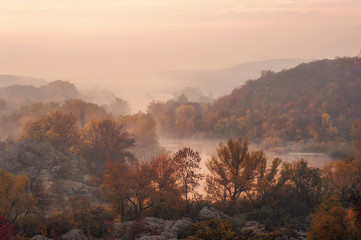 amazing aerial view of mountain rocks, blue foggy river and colorful forest on sunrise. autumn landscape