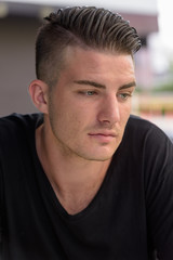 Fototapeta premium Young handsome man looking down while thinking outside the coffe