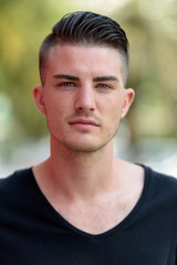 Fototapeta premium Face of young handsome man outdoors looking at camera