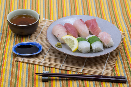 sushi plate with lemon slice, wasabi and soy sauce on bamboo set and colorful tablecloth