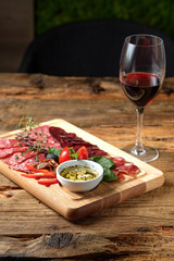 Glass of red wine and cutting board with assorted smoked meat