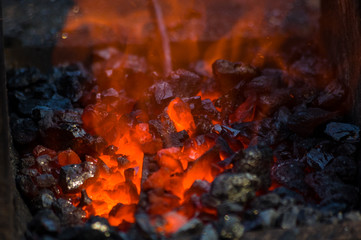 blacksmith furnace with burning coals, tools, and glowing hot metal workpieces