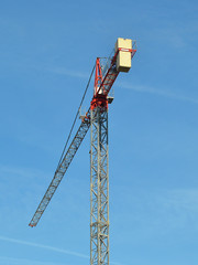 Tall construction tower crane against the blue sky on a day close up